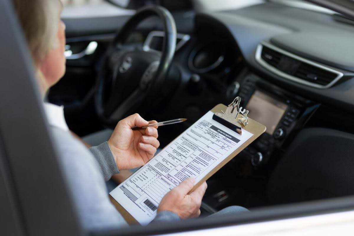 A imagem mostra uma pessoa em um carro, segurando uma prancheta e fazendo anotações com uma caneta.