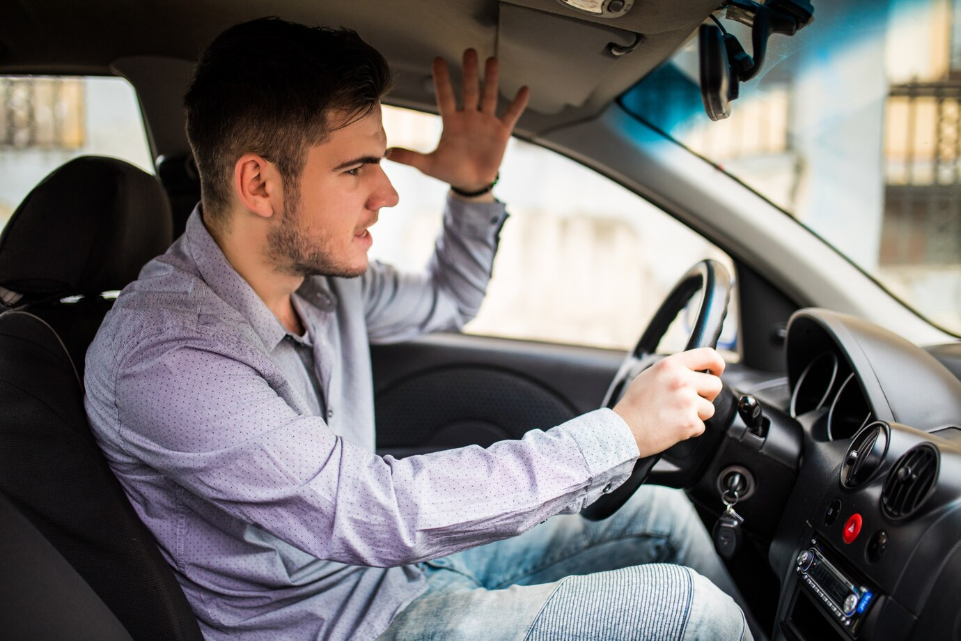 Imagem mostra um homem, aparentemente irritado, dirigindo um carro.