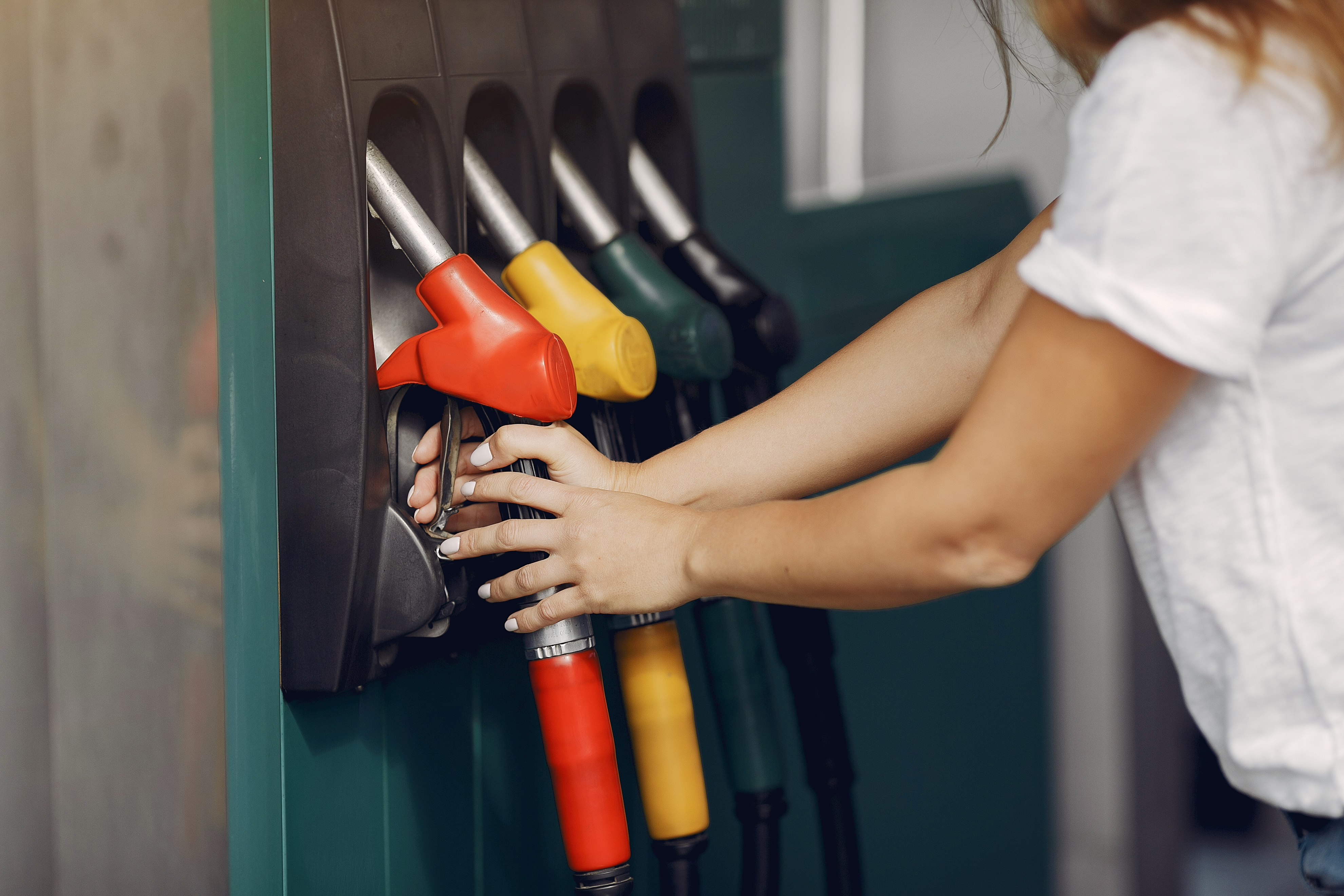 Close-up de uma mulher em um posto de gasolina escolhendo uma bomba de combustível para abastecer.