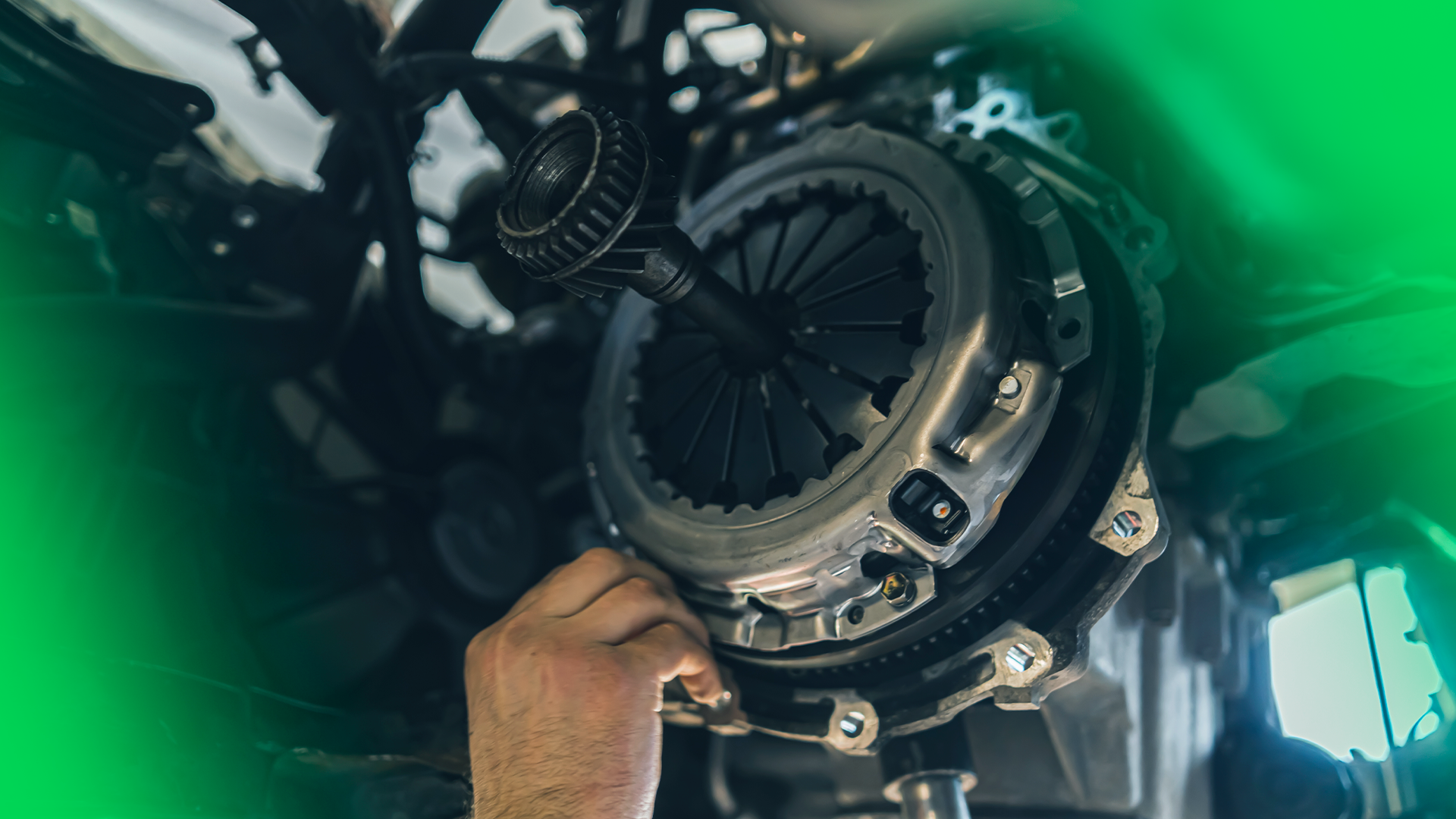 Imagem mostra mecânico (apenas sua mão) mexendo em sistema de embreagem de um carro