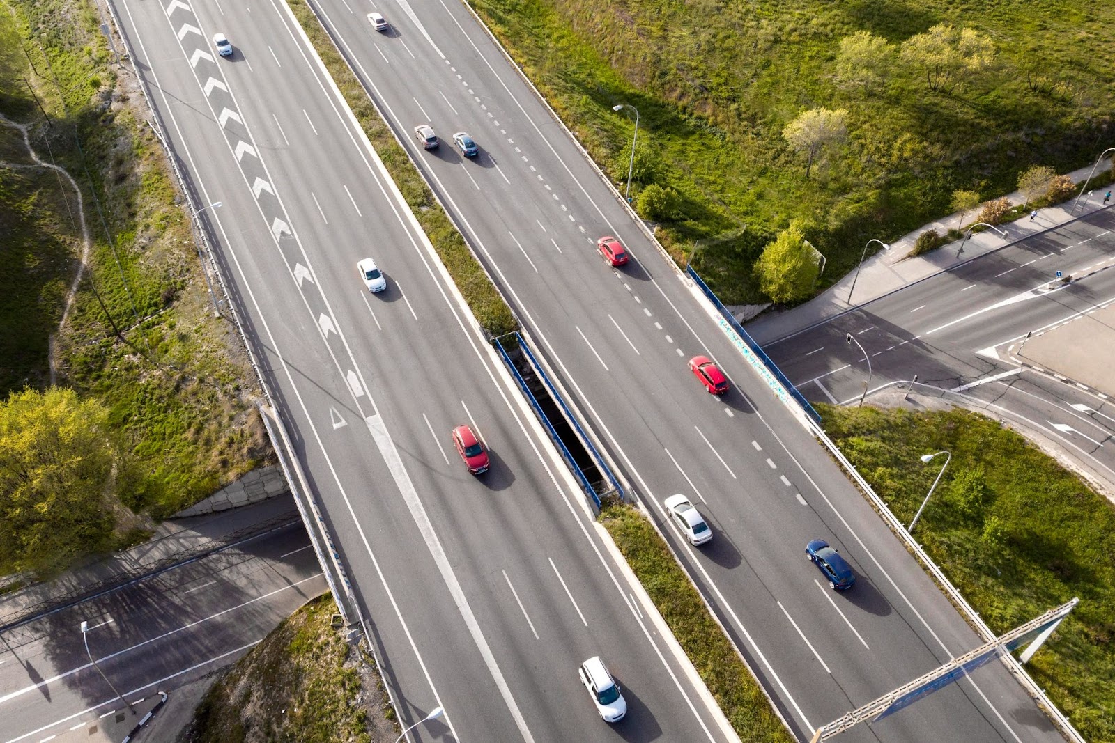 Imagem aérea de uma rodovia durante o dia de carros mantendo uma distância de seguimento segura no trânsito.