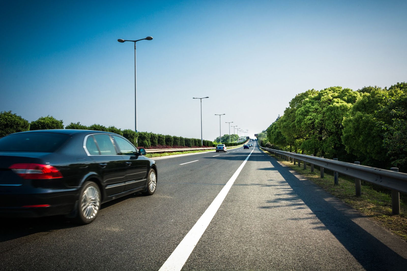 Na imagem de uma estrada durante o dia, vários carros podem ser observados mantendo uma distância de seguimento apropriada.