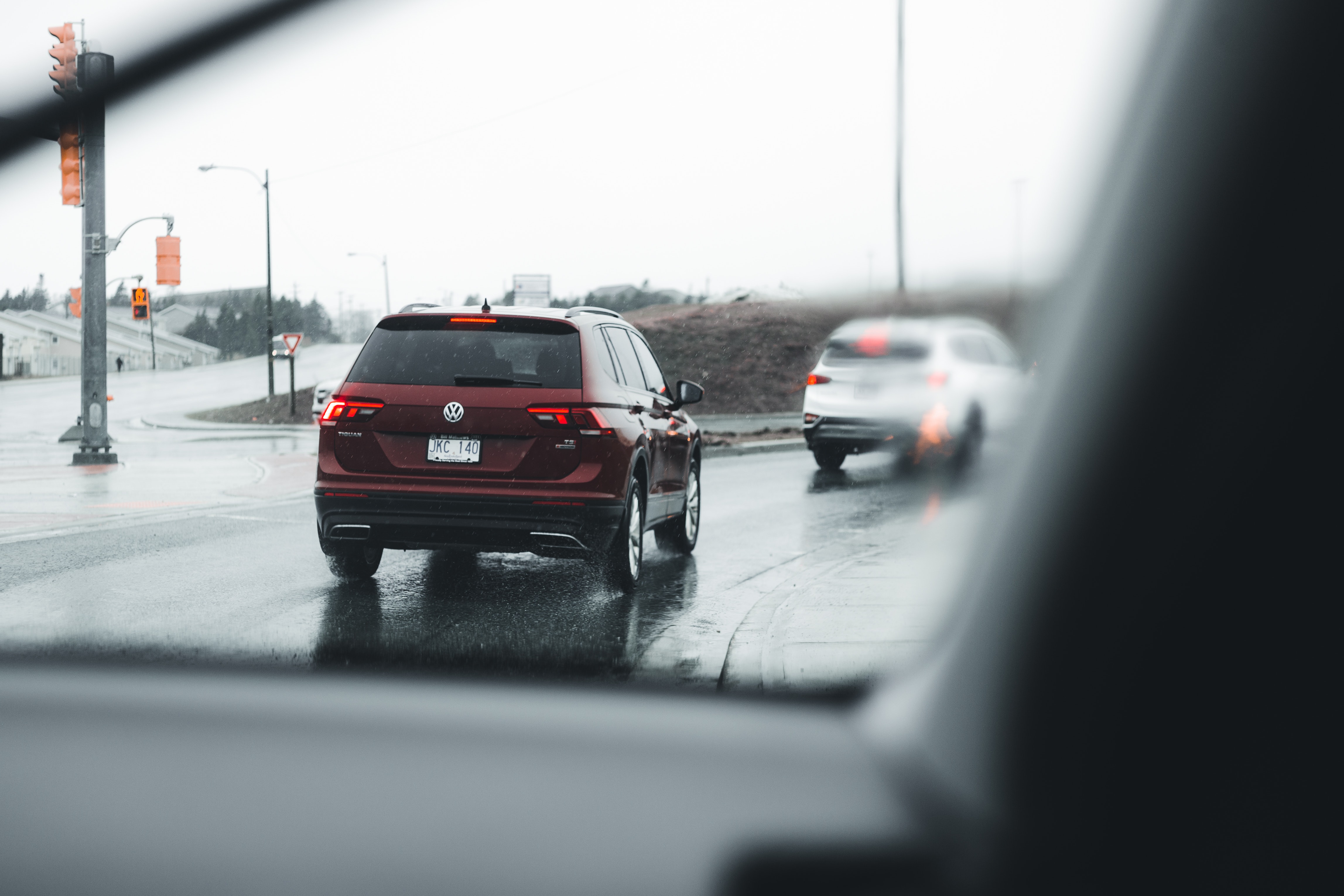 Imagem vista de dentro de um veículo de dois carros sendo dirigidos em dia chuvoso e em estrada molhada, mostrando o que é aquaplanagem.