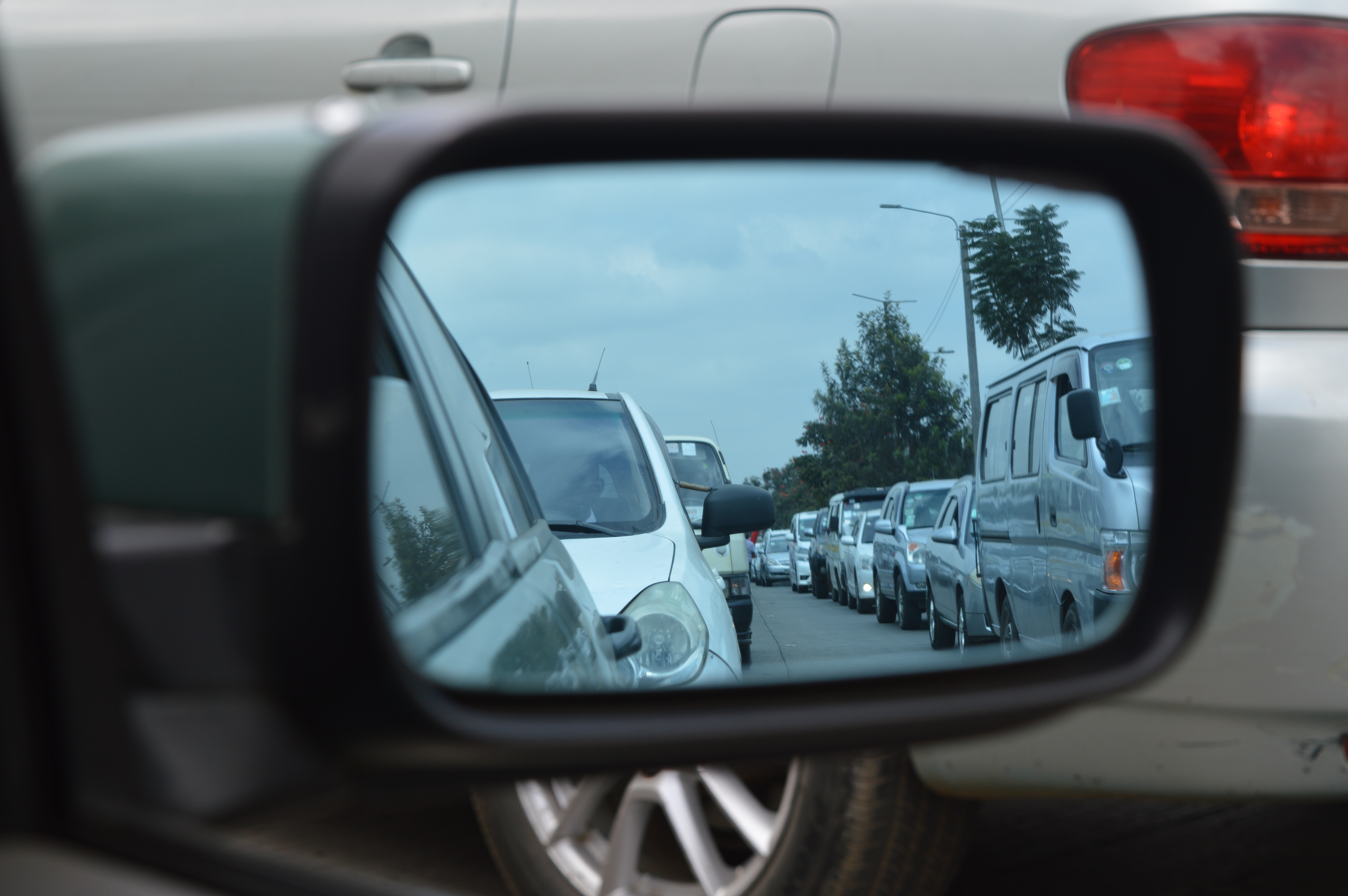 Imagem do reflexo de um retrovisor mostrando congestionamento de carros.