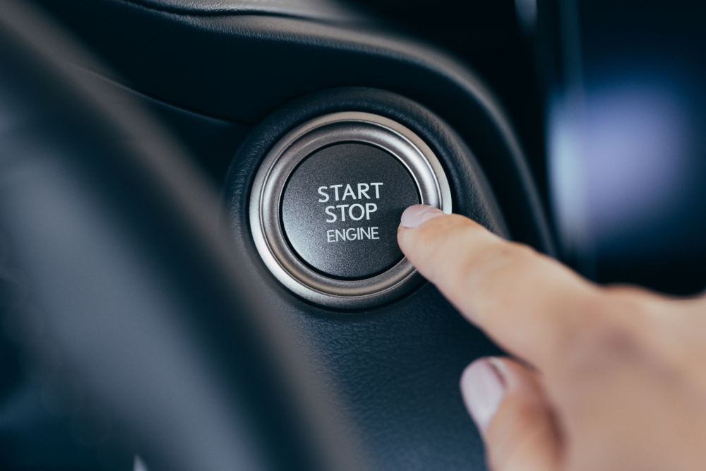 Close-up de uma pessoa pressionando o botão do sistema start stop.