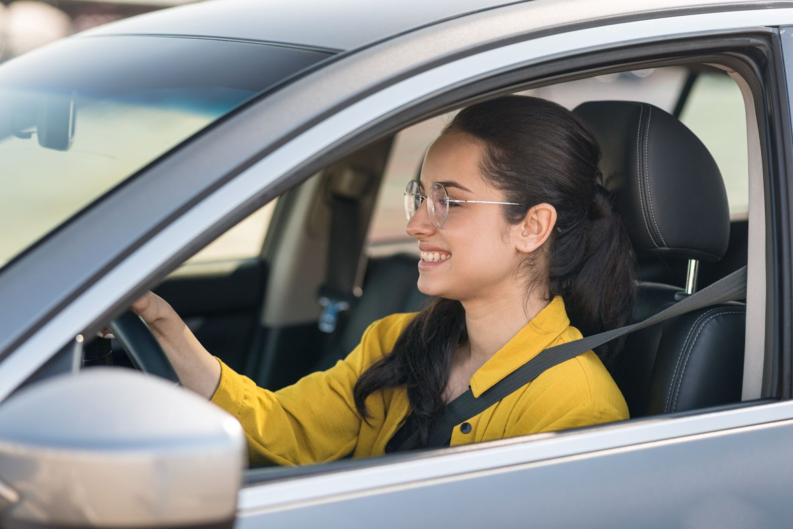 Mulher vestindo camisa amarela enquanto dirige seu veículo e observa as luzes do painel de carro.