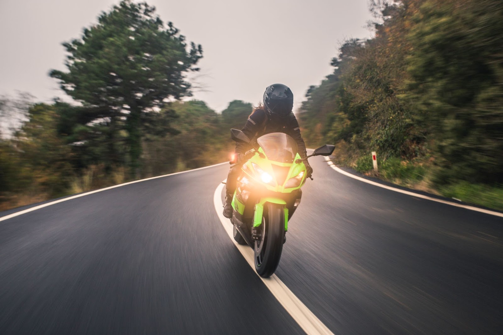 Motociclista em alta velocidade em estrada ao viajar de moto durante o dia.