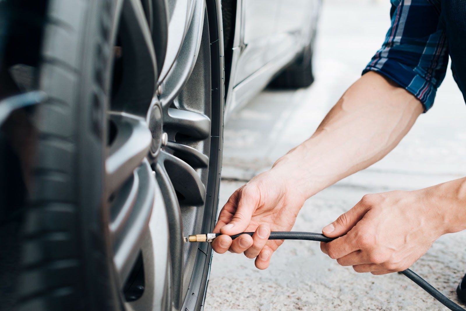 Close-up de um homem calibrando o pneu de um carro muito tempo parado.