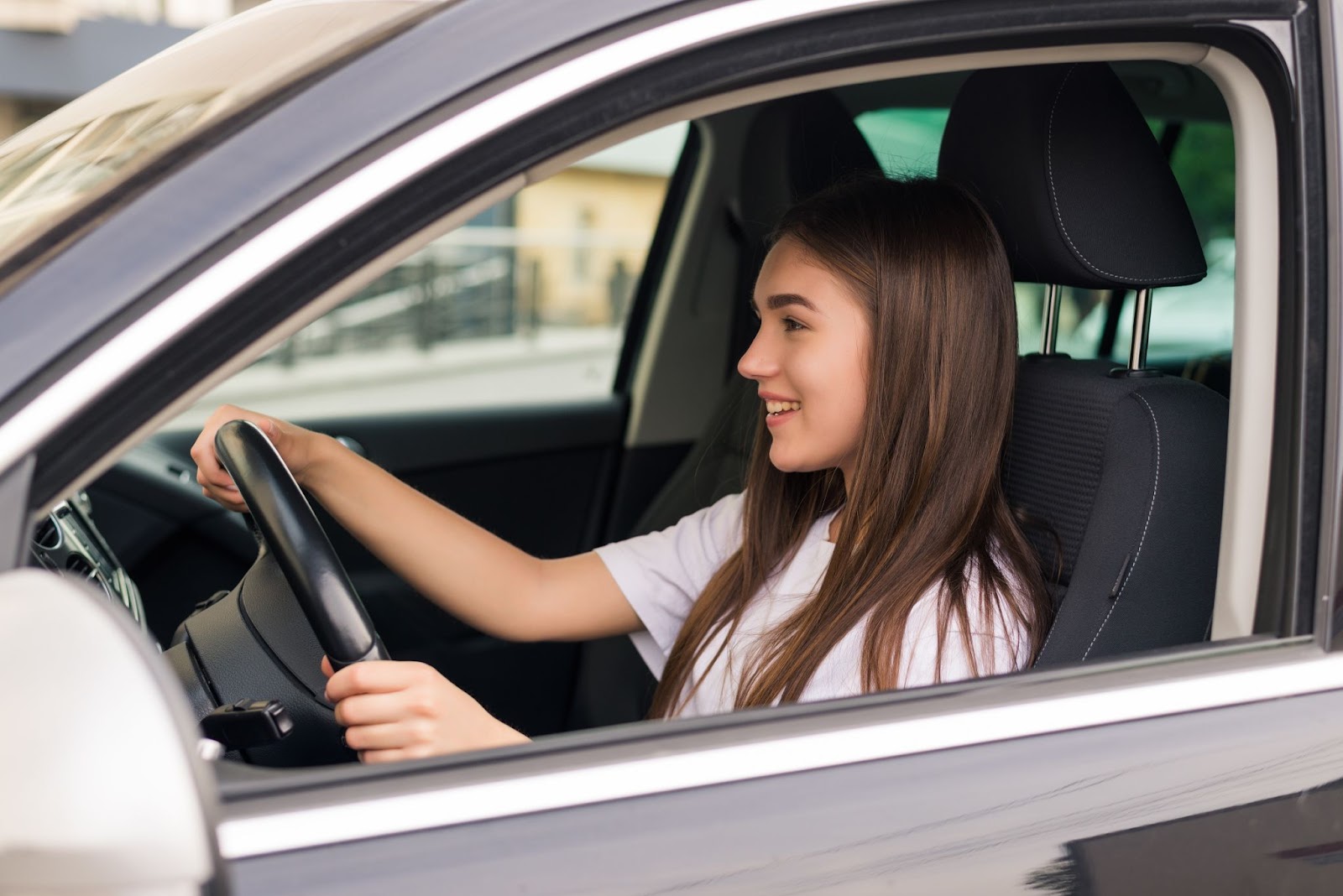 Mulher jovem vista da janela do seu carro enquanto dirige feliz e está satisfeita com o sistema de direção assistida.