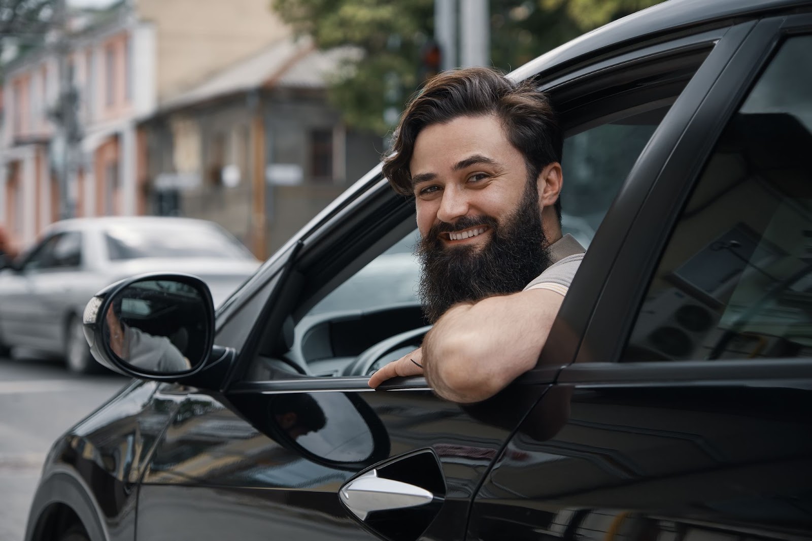Homem feliz dentro de um carro autônomo se apoiando para fora da janela. 