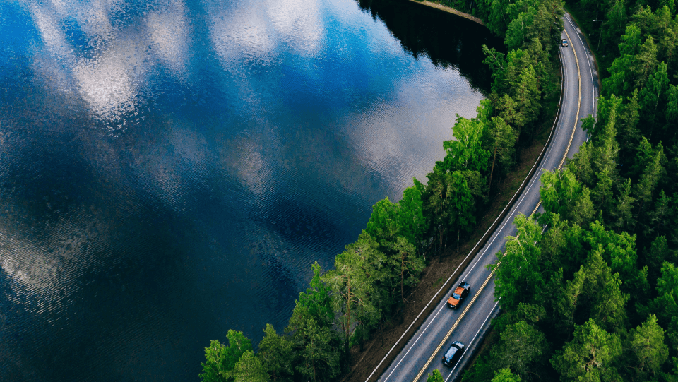 Overhead View of Cars Driving on the Open Road Adjacent Lake and Trees