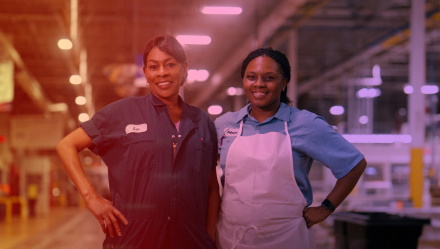 Two Female Employees Posing and Smiling in Factory